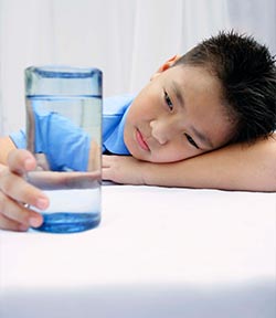 photo of boy eyeing water glass